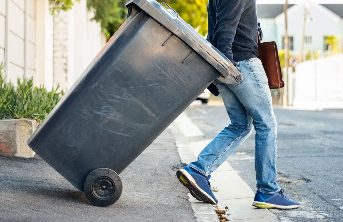 person taking trash can to the street